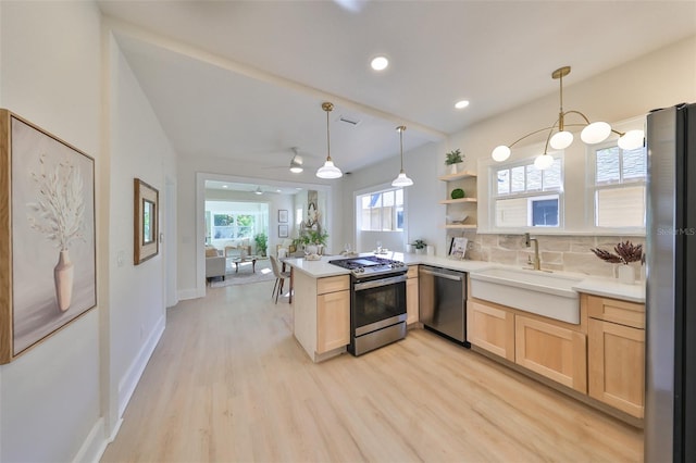 kitchen featuring hanging light fixtures, kitchen peninsula, backsplash, light wood-type flooring, and appliances with stainless steel finishes