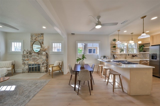 kitchen featuring a kitchen breakfast bar, light hardwood / wood-style flooring, stainless steel fridge with ice dispenser, decorative light fixtures, and tasteful backsplash