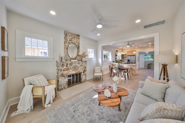 living room featuring a fireplace, light wood-type flooring, and plenty of natural light