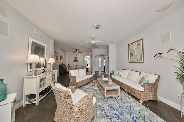 living room with dark tile patterned flooring, a textured ceiling, and ceiling fan