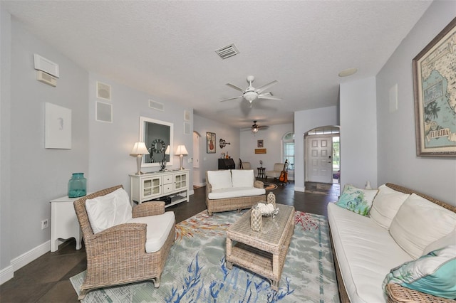 living room featuring ceiling fan, a textured ceiling, and dark tile patterned flooring