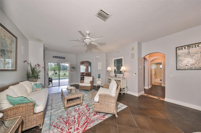 living room featuring dark tile patterned flooring, a textured ceiling, and ceiling fan