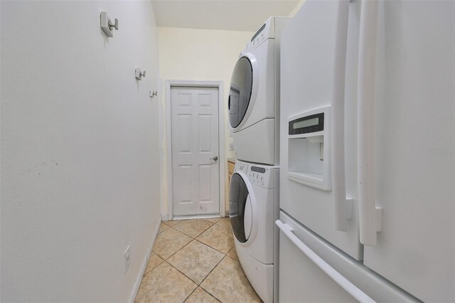 clothes washing area featuring light tile patterned floors and stacked washer and dryer