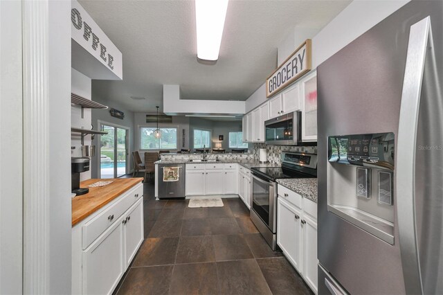 kitchen with white cabinets, sink, appliances with stainless steel finishes, and kitchen peninsula