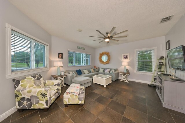 living room with a textured ceiling, ceiling fan, and a wealth of natural light