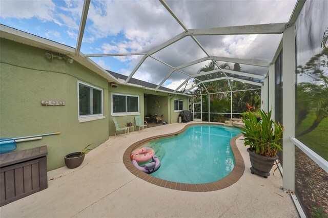 view of pool with glass enclosure, a grill, and a patio area