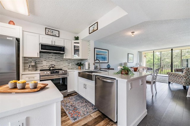 kitchen featuring stainless steel appliances, white cabinetry, kitchen peninsula, and sink