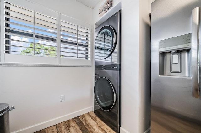 clothes washing area with wood-type flooring and stacked washer and clothes dryer