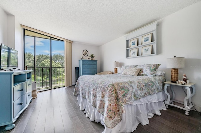 bedroom featuring access to outside, a wall of windows, dark wood-type flooring, and a textured ceiling