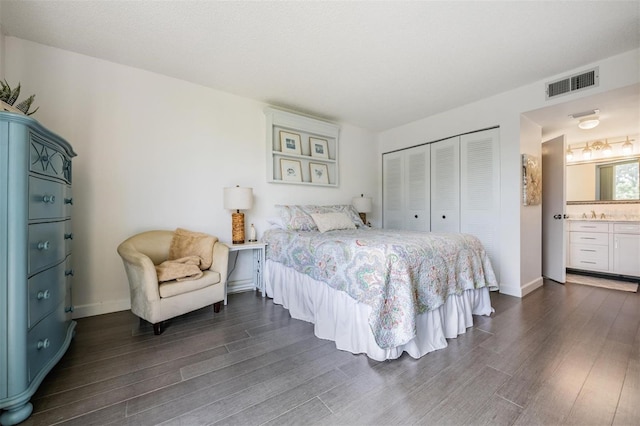 bedroom with a closet, ensuite bath, and dark hardwood / wood-style flooring