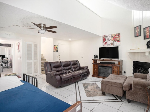 living room with ceiling fan, light tile patterned flooring, and a textured ceiling