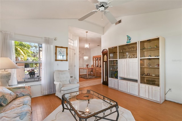 living room with ceiling fan with notable chandelier, wood-type flooring, and lofted ceiling