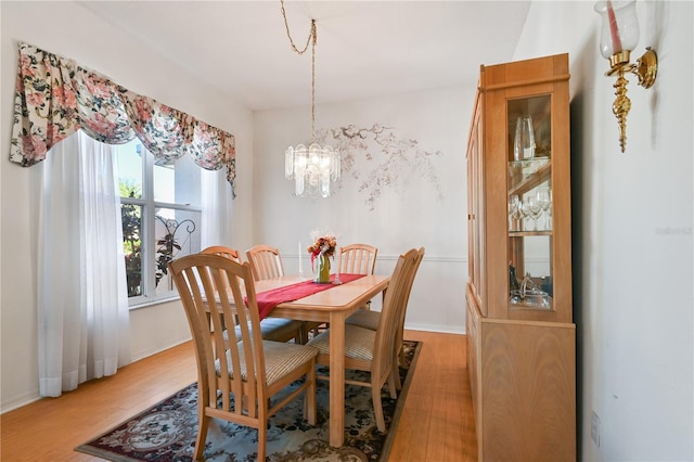 dining space featuring hardwood / wood-style flooring and an inviting chandelier