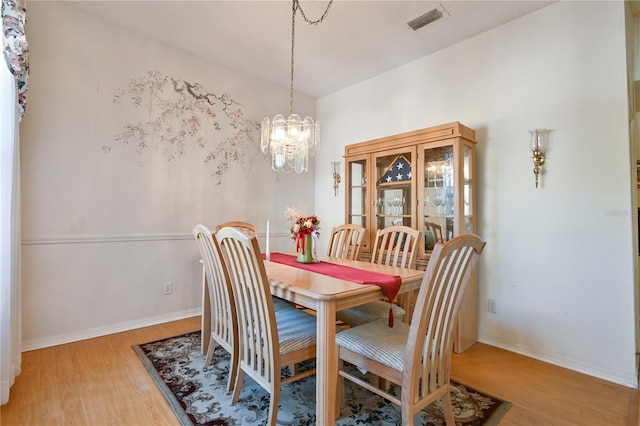 dining area featuring hardwood / wood-style floors and an inviting chandelier