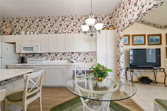 kitchen with white cabinets, light wood-type flooring, white appliances, and decorative light fixtures