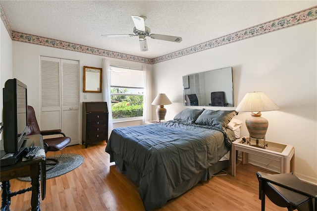 bedroom featuring a closet, ceiling fan, light hardwood / wood-style flooring, and a textured ceiling