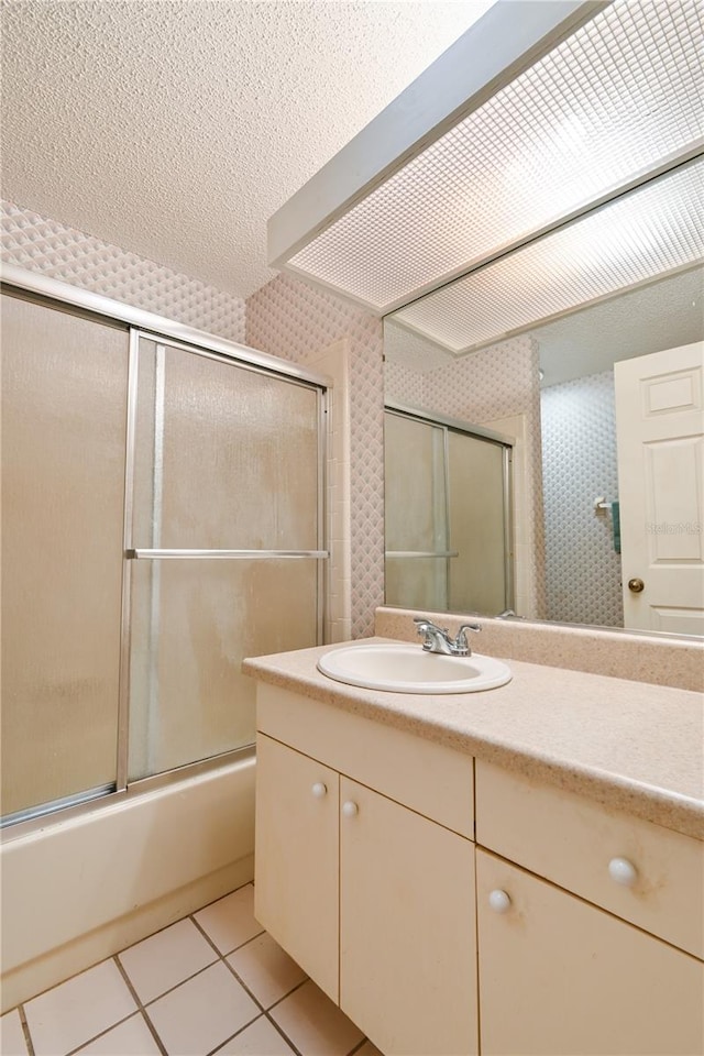 bathroom featuring tile patterned flooring, vanity, enclosed tub / shower combo, and a textured ceiling