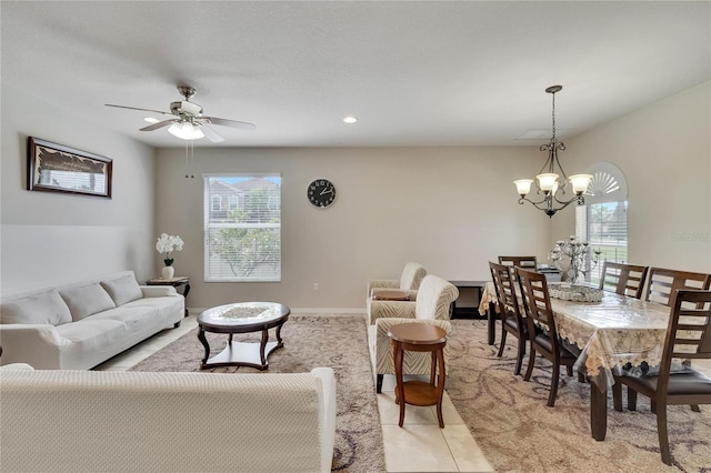 tiled living room featuring a healthy amount of sunlight and ceiling fan with notable chandelier