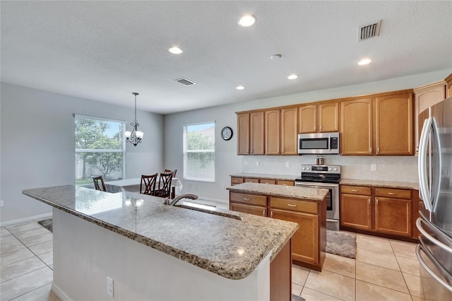 kitchen with hanging light fixtures, sink, a kitchen island with sink, stainless steel appliances, and an inviting chandelier