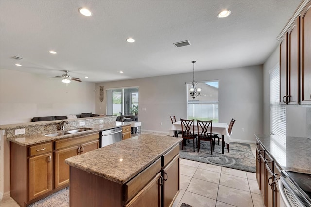 kitchen with appliances with stainless steel finishes, hanging light fixtures, ceiling fan with notable chandelier, a kitchen island, and sink