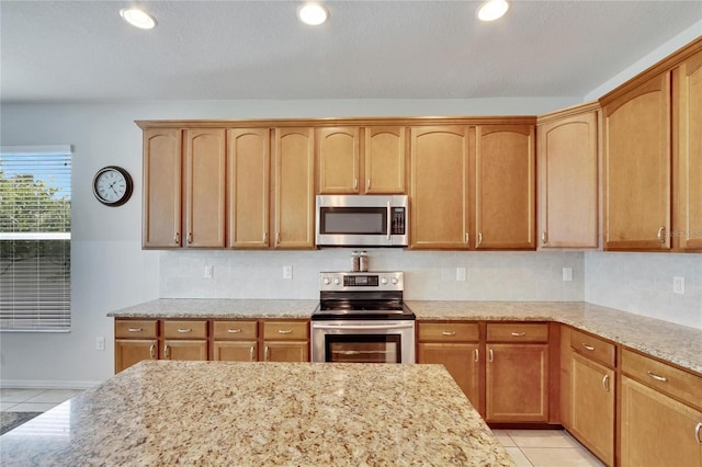 kitchen featuring decorative backsplash, light tile patterned floors, stainless steel appliances, and light stone counters