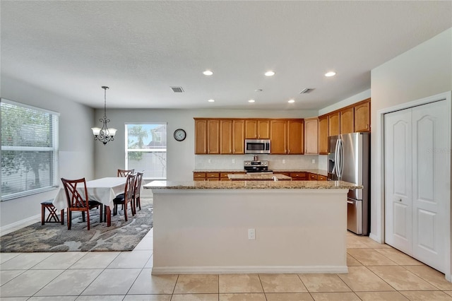 kitchen with decorative light fixtures, light tile patterned flooring, stainless steel appliances, and light stone counters