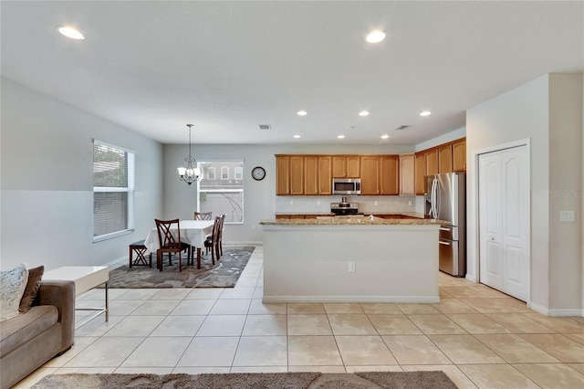 kitchen featuring appliances with stainless steel finishes, light stone counters, light tile patterned floors, decorative light fixtures, and a notable chandelier