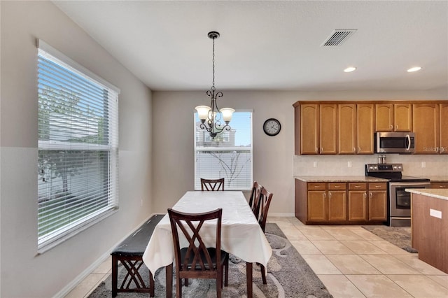 tiled dining room with an inviting chandelier