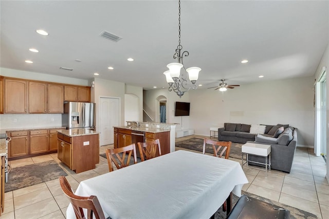 dining area with light tile patterned flooring, ceiling fan with notable chandelier, and sink