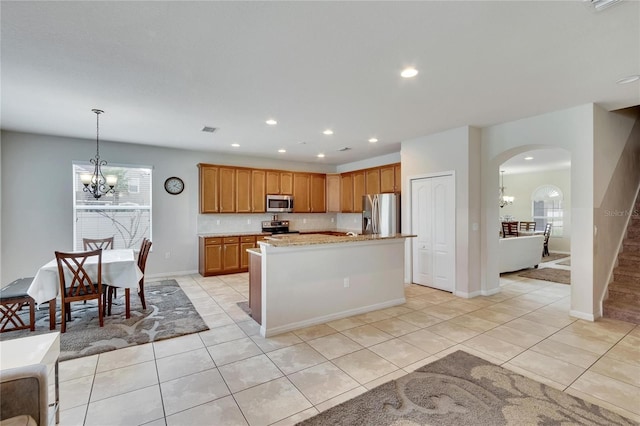 kitchen with decorative light fixtures, light tile patterned flooring, stainless steel appliances, and a center island