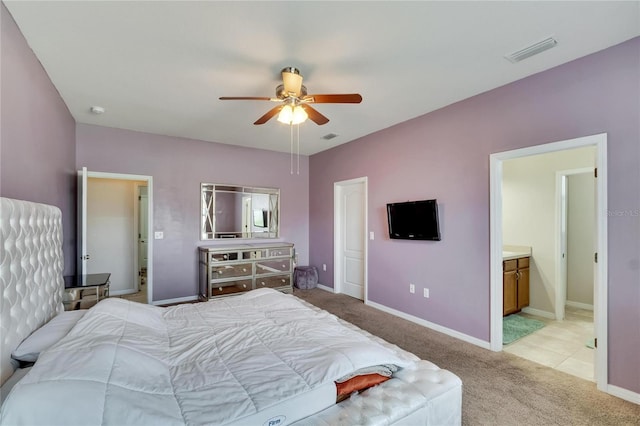 bedroom featuring ceiling fan, light colored carpet, and ensuite bathroom