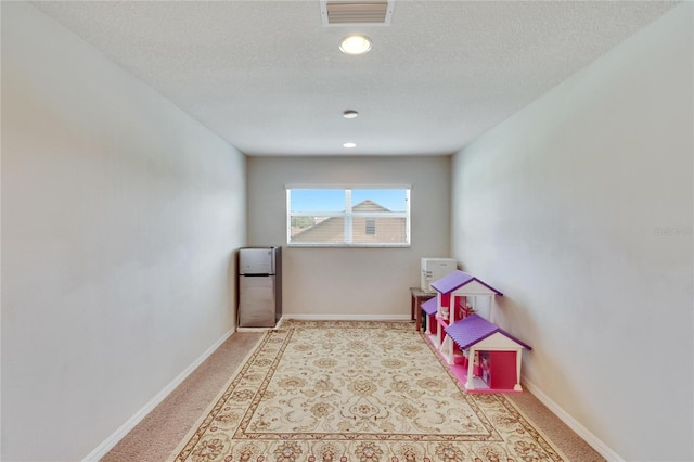 playroom with a textured ceiling and light colored carpet