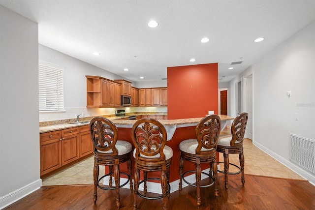 1030 Bellasol Way Unit 201, Apollo Beach, FL 33572 - kitchen with appliances with stainless steel finishes, open shelves, a sink, a breakfast bar area, and recessed lighting