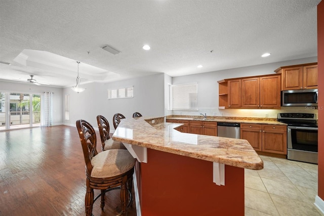 1030 Bellasol Way Unit 201, Apollo Beach, FL 33572 - kitchen with stainless steel appliances, a sink, a breakfast bar area, a textured ceiling, and recessed lighting