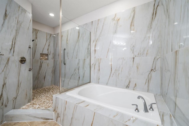 1030 Bellasol Way Unit 201, Apollo Beach, FL 33572 - full bathroom featuring a garden tub, a marble finish shower, a textured ceiling, recessed lighting, and tile walls