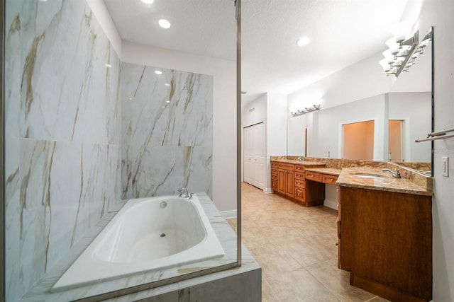 bathroom with vanity, a textured ceiling, tile patterned flooring, and tiled tub