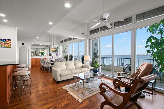 living room featuring a water view, ceiling fan, and dark wood-type flooring