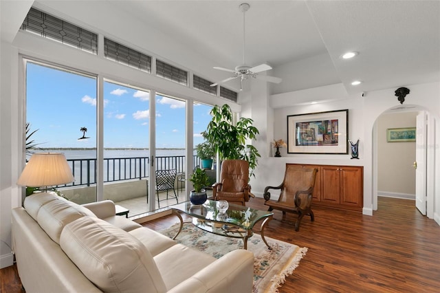 living room with a water view, dark hardwood / wood-style flooring, and ceiling fan