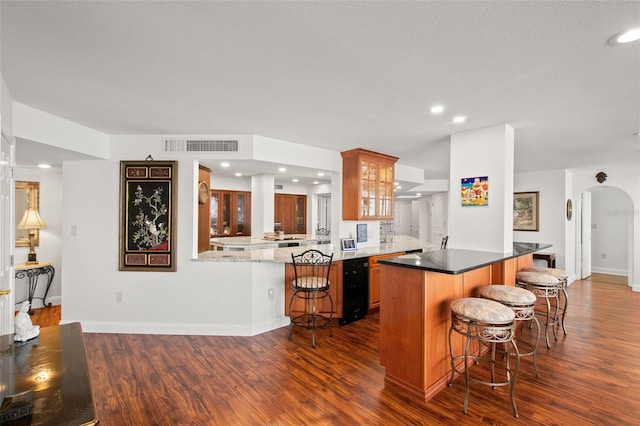 kitchen featuring a kitchen breakfast bar, kitchen peninsula, and dark hardwood / wood-style flooring