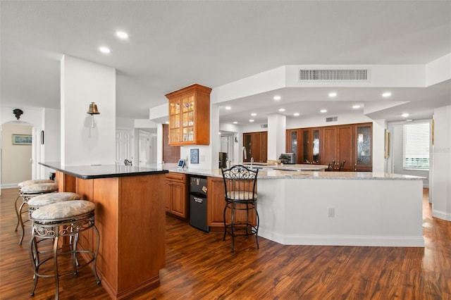 kitchen featuring kitchen peninsula, a kitchen bar, and dark hardwood / wood-style flooring