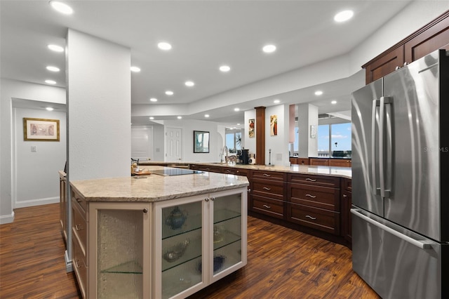 kitchen featuring light stone counters, stainless steel fridge, sink, a center island, and dark hardwood / wood-style flooring