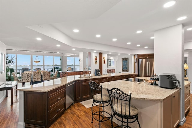 kitchen featuring a kitchen breakfast bar, stainless steel appliances, light stone countertops, and sink