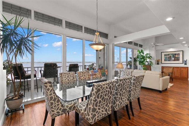 dining space with a water view, ceiling fan, and dark wood-type flooring