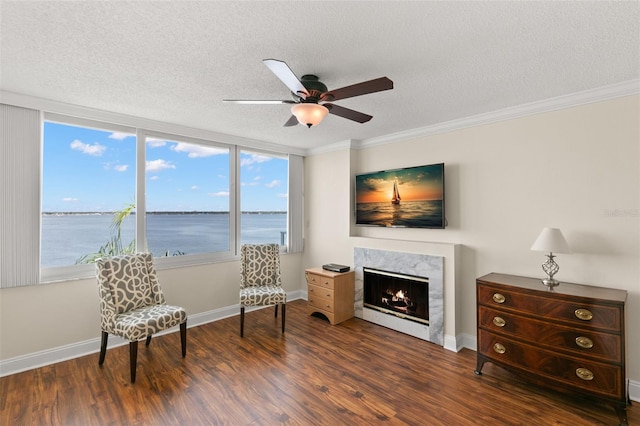 sitting room with a textured ceiling, ornamental molding, dark wood-type flooring, and a premium fireplace