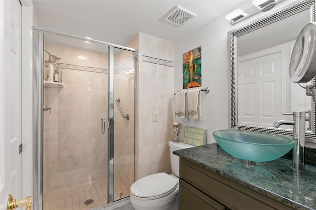 bathroom with vanity, toilet, and a shower with door