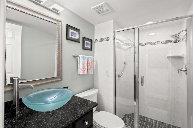 bathroom featuring vanity, toilet, and a shower with shower door