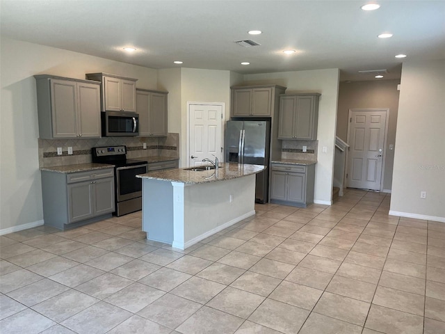 kitchen featuring a center island with sink, appliances with stainless steel finishes, sink, and gray cabinetry