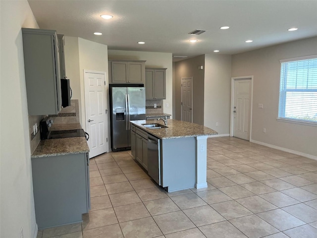 kitchen featuring black appliances, decorative backsplash, sink, and an island with sink