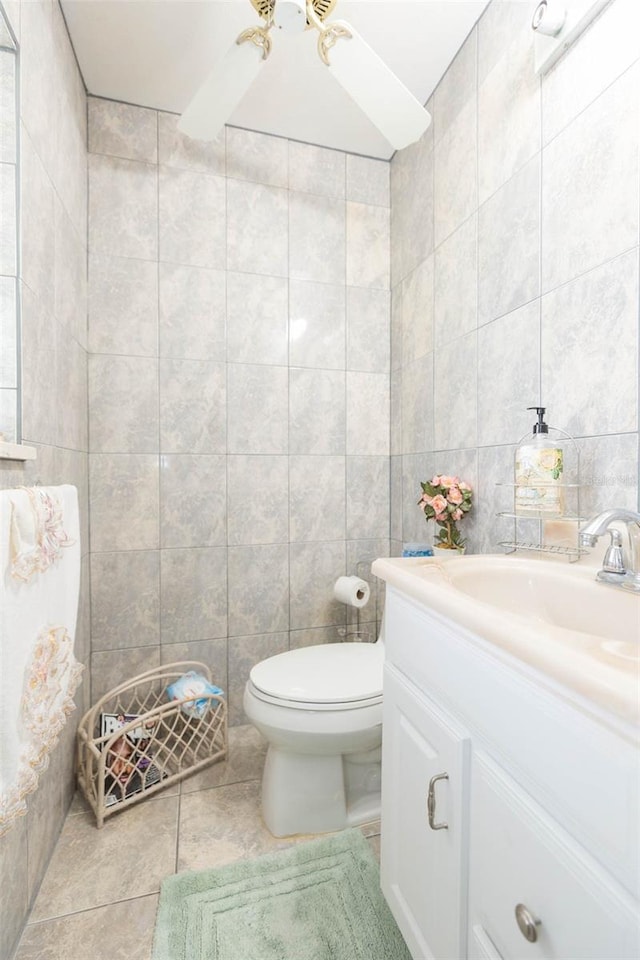 bathroom featuring tile walls, tile patterned floors, ceiling fan, vanity, and toilet