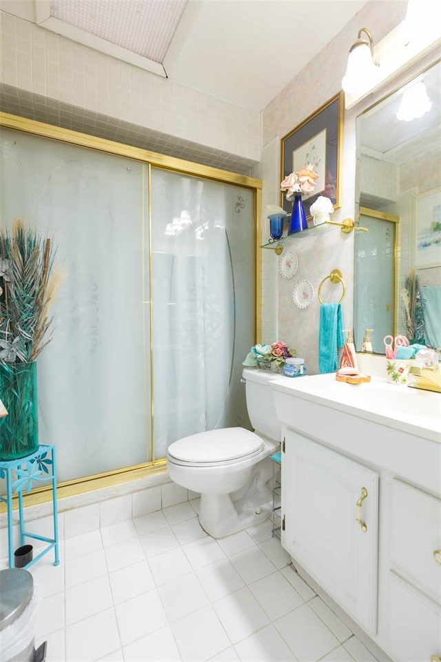 bathroom with tile patterned flooring, a shower with door, vanity, and toilet